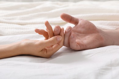 Lovely couple holding hands in bed, closeup