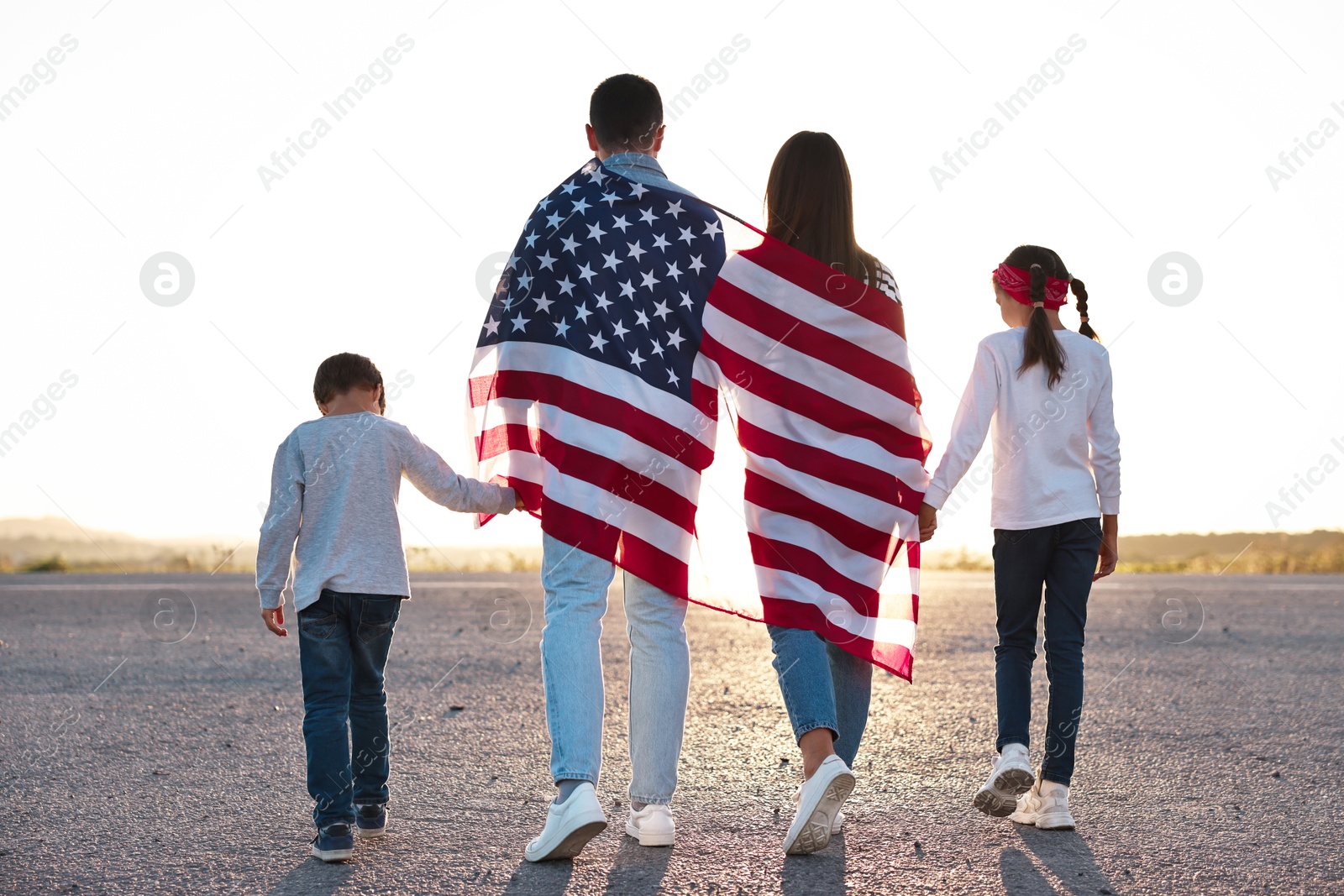 Photo of Family with flag of USA walking outdoors, back view