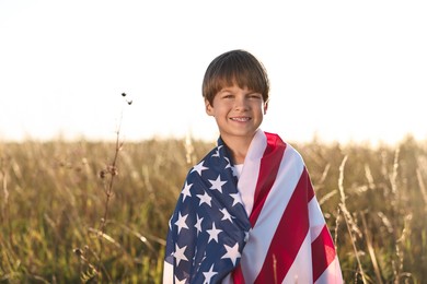 Portrait of happy boy with flag of USA outdoors. Space for text