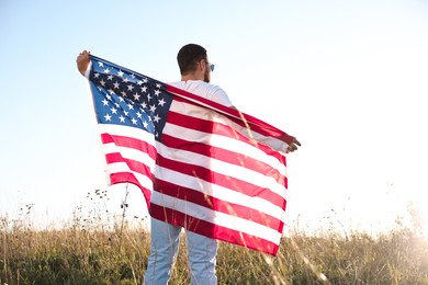 Photo of Man with flag of USA outdoors, back view