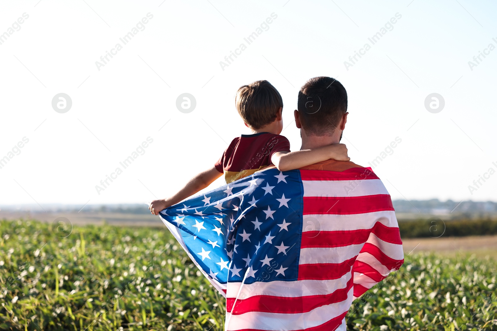 Photo of Father and son with flag of USA outdoors. back view. Space for text