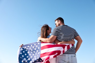 Photo of Couple with flag of USA outdoors, back view. Space for text