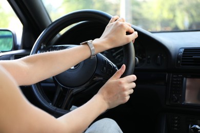 Woman holding steering wheel while driving car, closeup