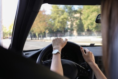 Woman holding steering wheel while driving car, closeup