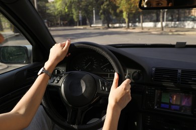 Woman holding steering wheel while driving car, closeup