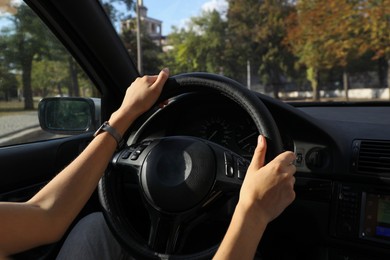 Woman holding steering wheel while driving car, closeup