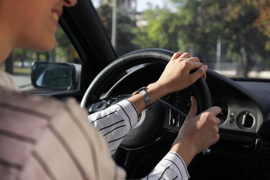 Woman holding steering wheel while driving car, closeup