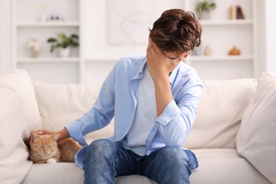 Loneliness concept. Sad teenage boy with cute cat on sofa at home