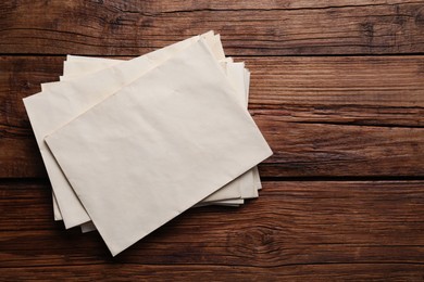 Photo of Old letter envelopes on wooden table, top view. Space for text