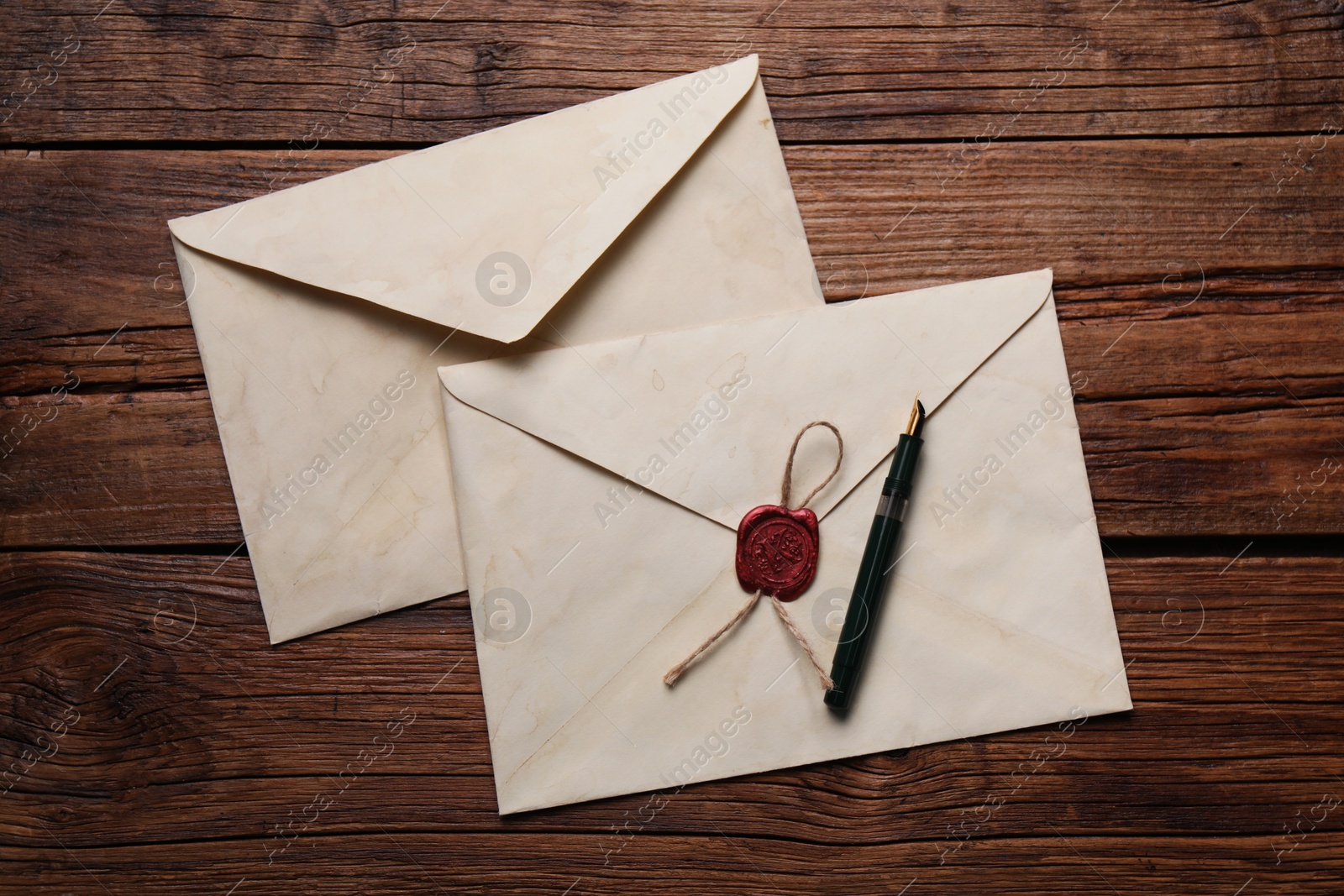 Photo of Old letter envelopes and pen on wooden table, top view