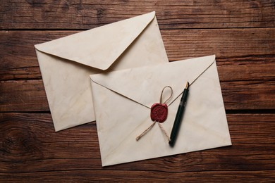 Old letter envelopes and pen on wooden table, top view