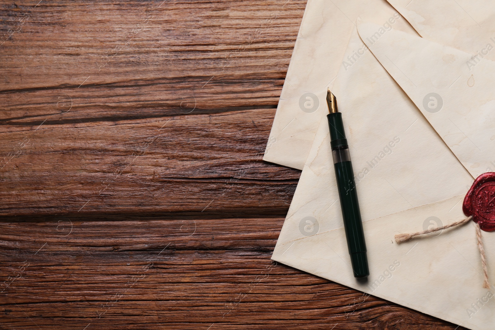 Photo of Old letter envelopes and pen on wooden table, top view. Space for text