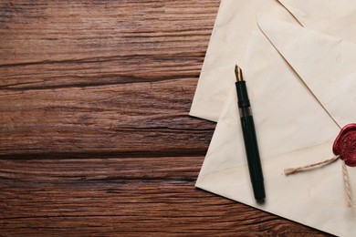 Old letter envelopes and pen on wooden table, top view. Space for text