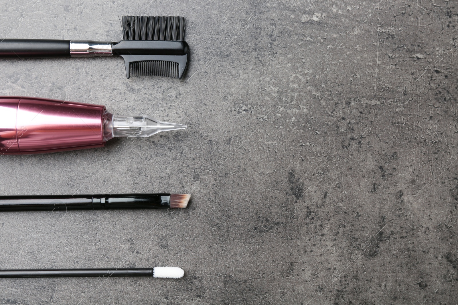 Photo of Professional permanent makeup machine and different brushes on grey background, flat lay. Space for text