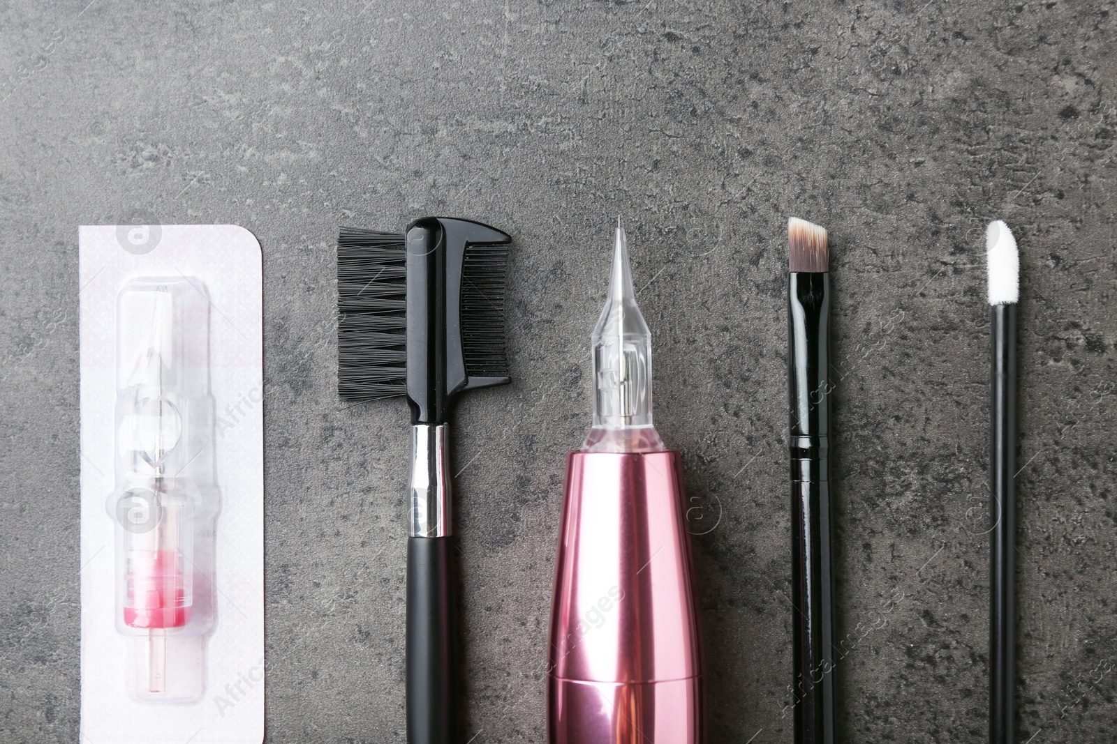 Photo of Professional permanent makeup machine, disposable cartridge system and different brushes on grey background, flat lay