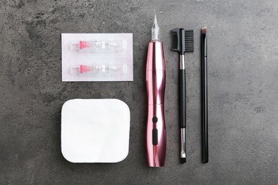 Photo of Professional permanent makeup machine, disposable cartridge systems and different brushes on grey background, flat lay