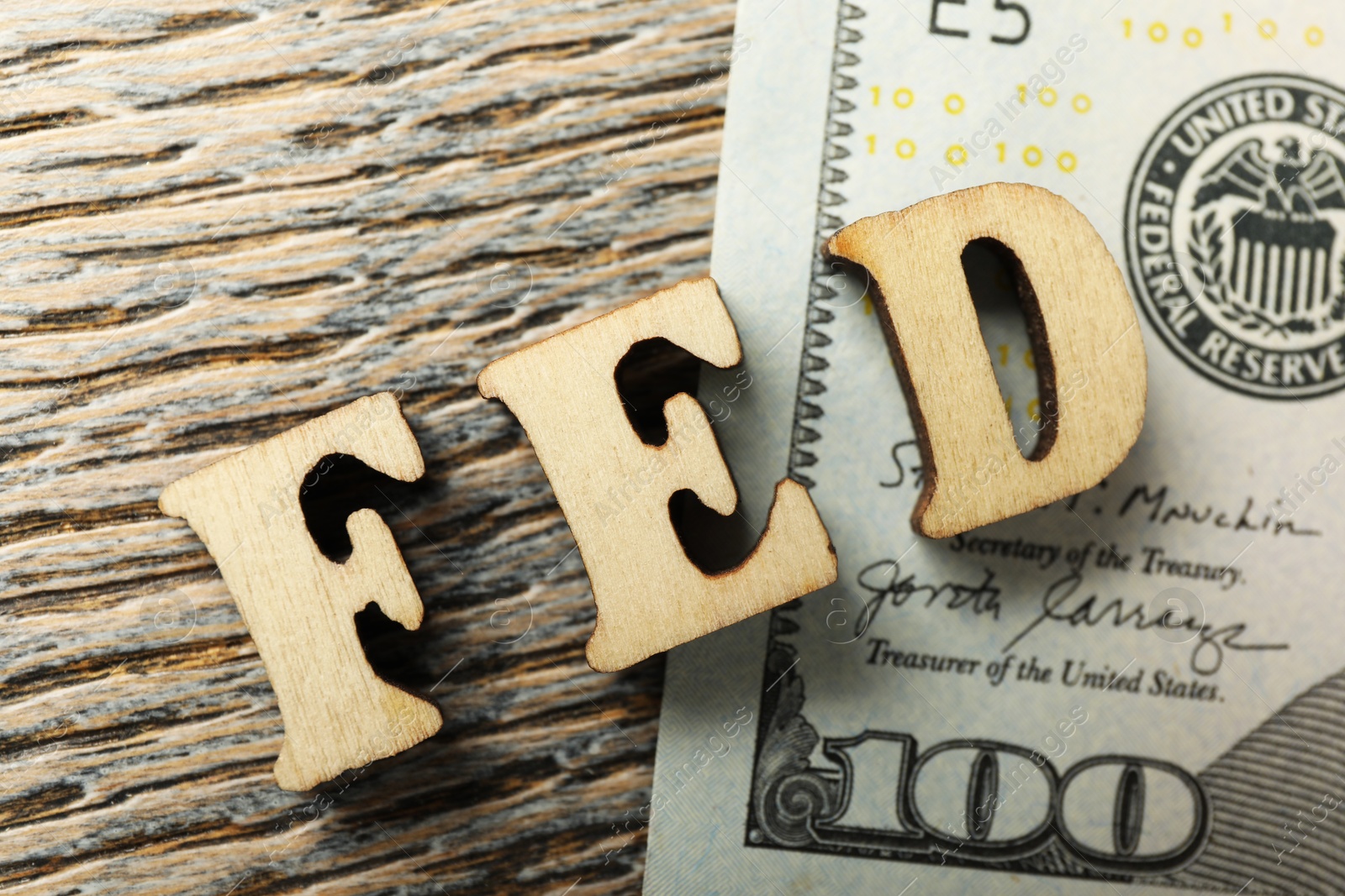 Photo of Letters Fed (Federal Reserve System) and dollar banknote on wooden table, flat lay