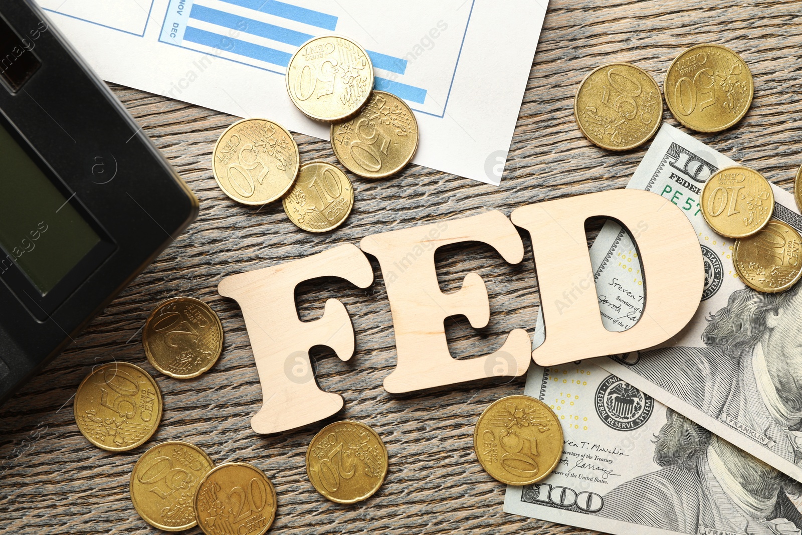 Photo of Letters Fed (Federal Reserve System), coins, dollar banknotes and calculator on wooden table, flat lay