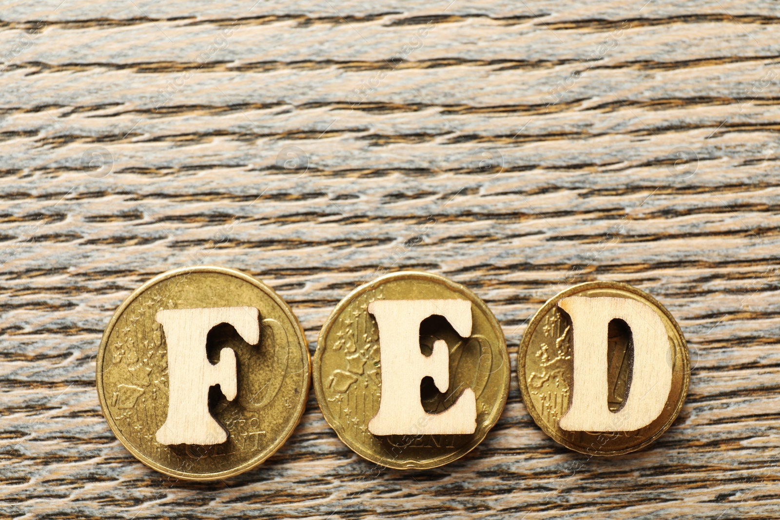 Photo of Letters Fed (Federal Reserve System) and coins on wooden table, flat lay. Space for text