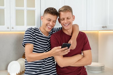 Happy brothers looking at smartphone in kitchen