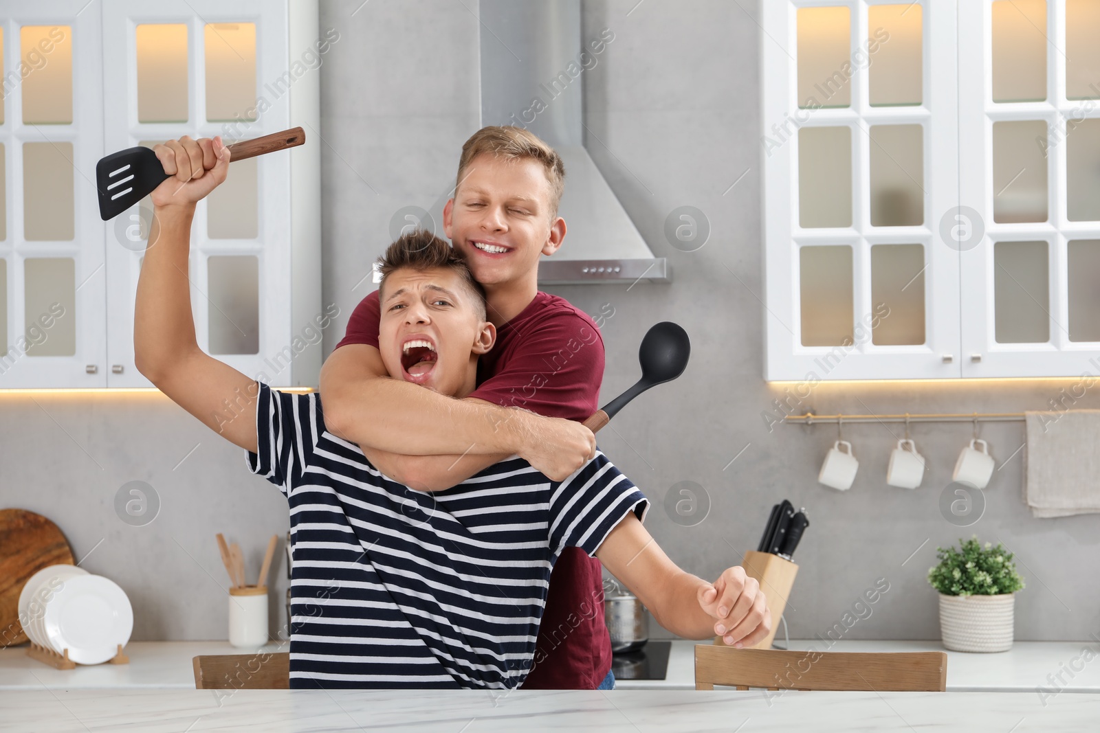 Photo of Two happy brothers having fun in kitchen