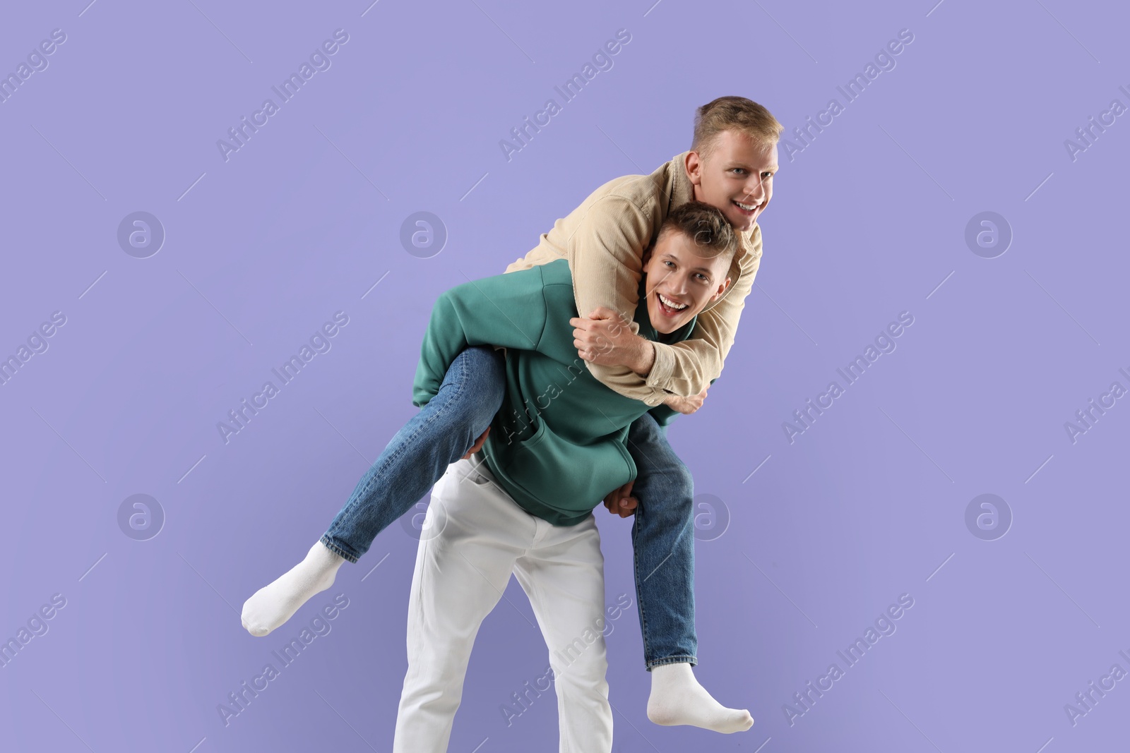 Photo of Happy brothers having fun on violet background. Space for text