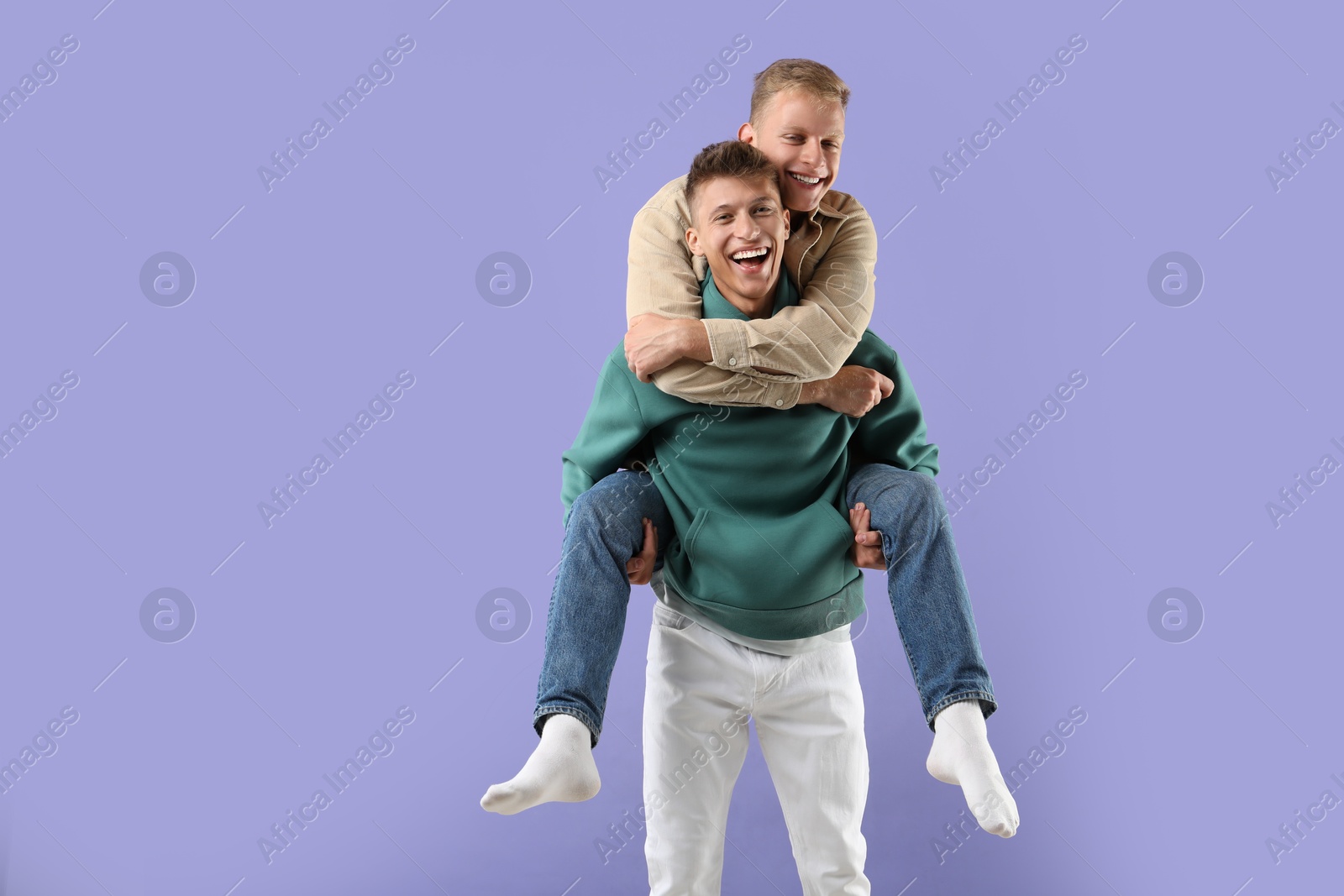 Photo of Happy brothers having fun on violet background. Space for text