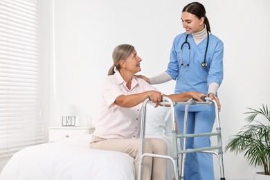 Nurse helping senior woman with walking frame in clinic