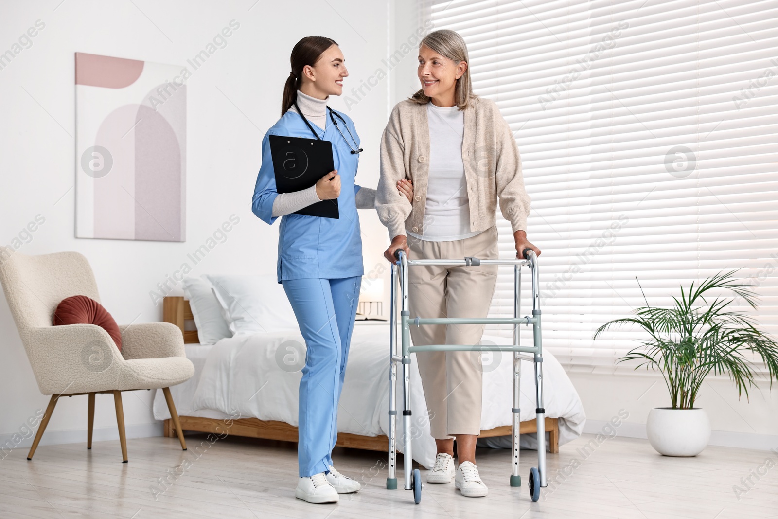 Photo of Nurse helping senior woman with walking frame in clinic