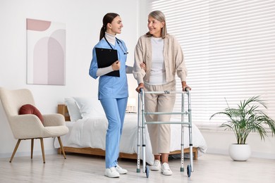 Nurse helping senior woman with walking frame in clinic