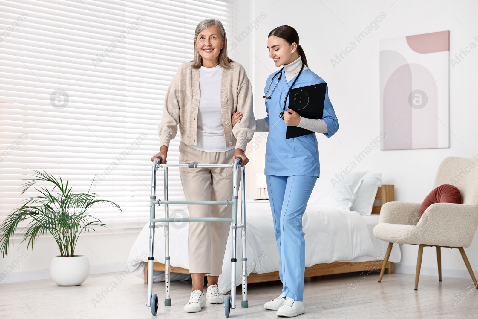 Photo of Nurse helping senior woman with walking frame in clinic