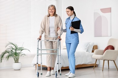 Photo of Nurse helping senior woman with walking frame in clinic