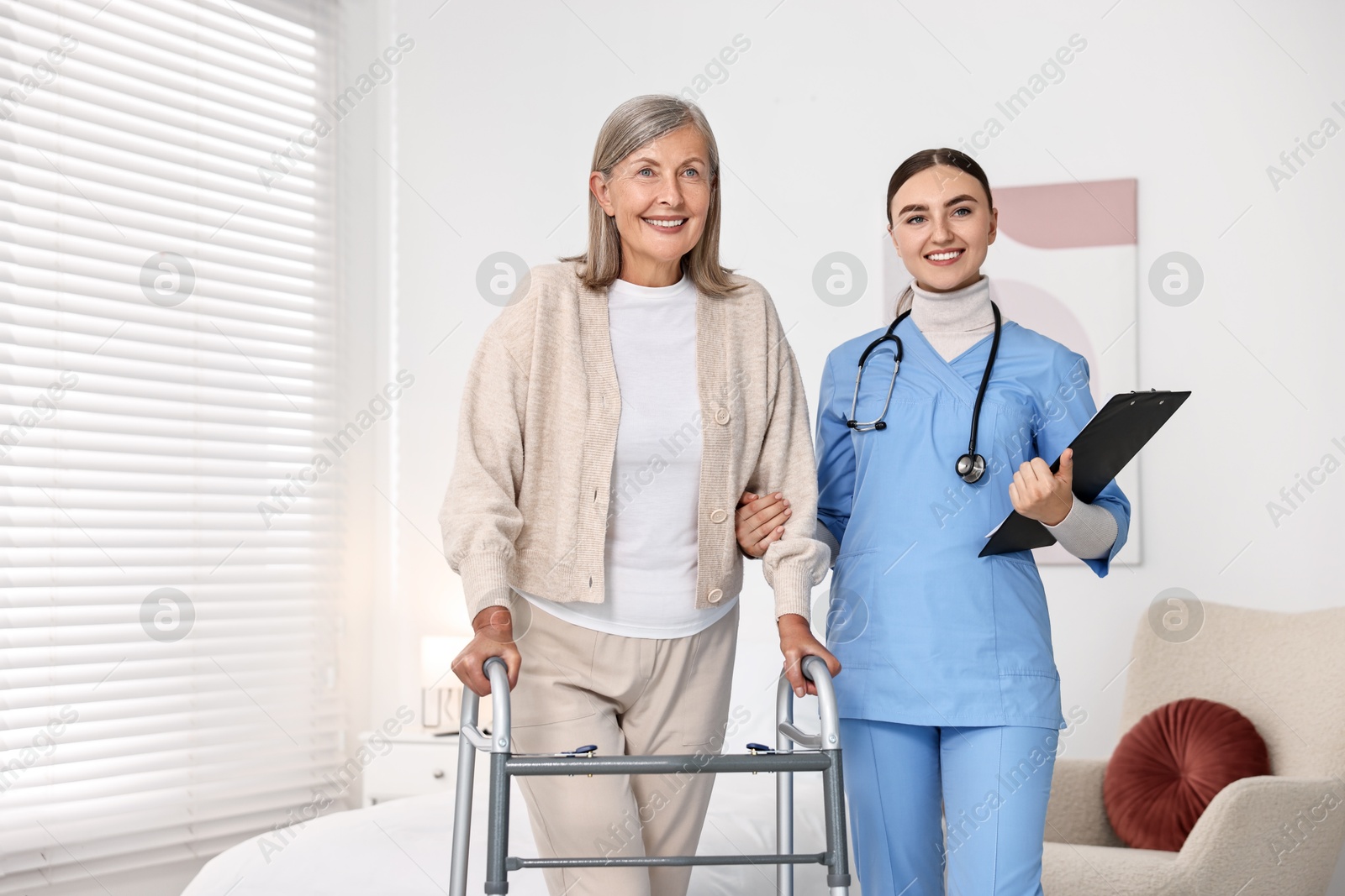 Photo of Nurse helping senior woman with walking frame in clinic