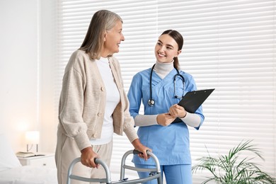 Nurse helping senior woman with walking frame in clinic