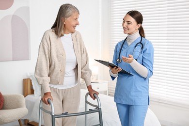 Nurse helping senior woman with walking frame in clinic