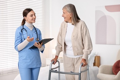 Nurse helping senior woman with walking frame in clinic