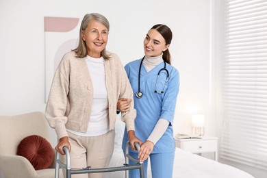 Nurse helping senior woman with walking frame in clinic