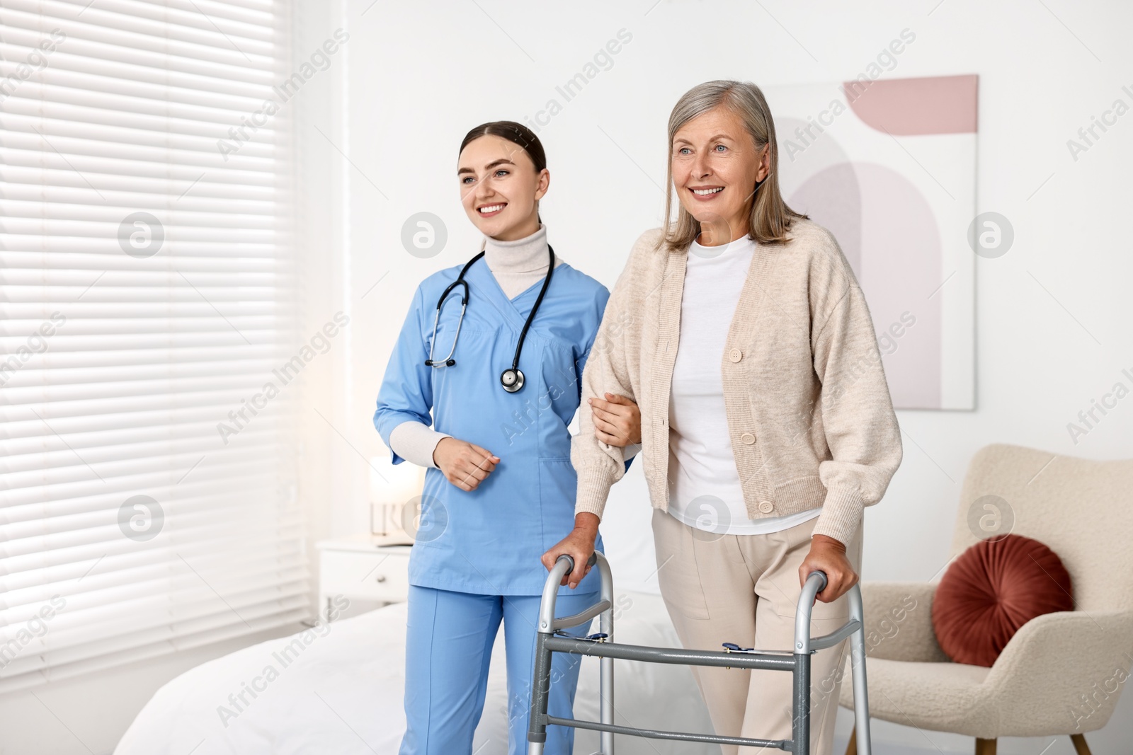 Photo of Nurse helping senior woman with walking frame in clinic