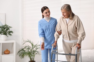 Nurse helping senior woman with walking frame in clinic