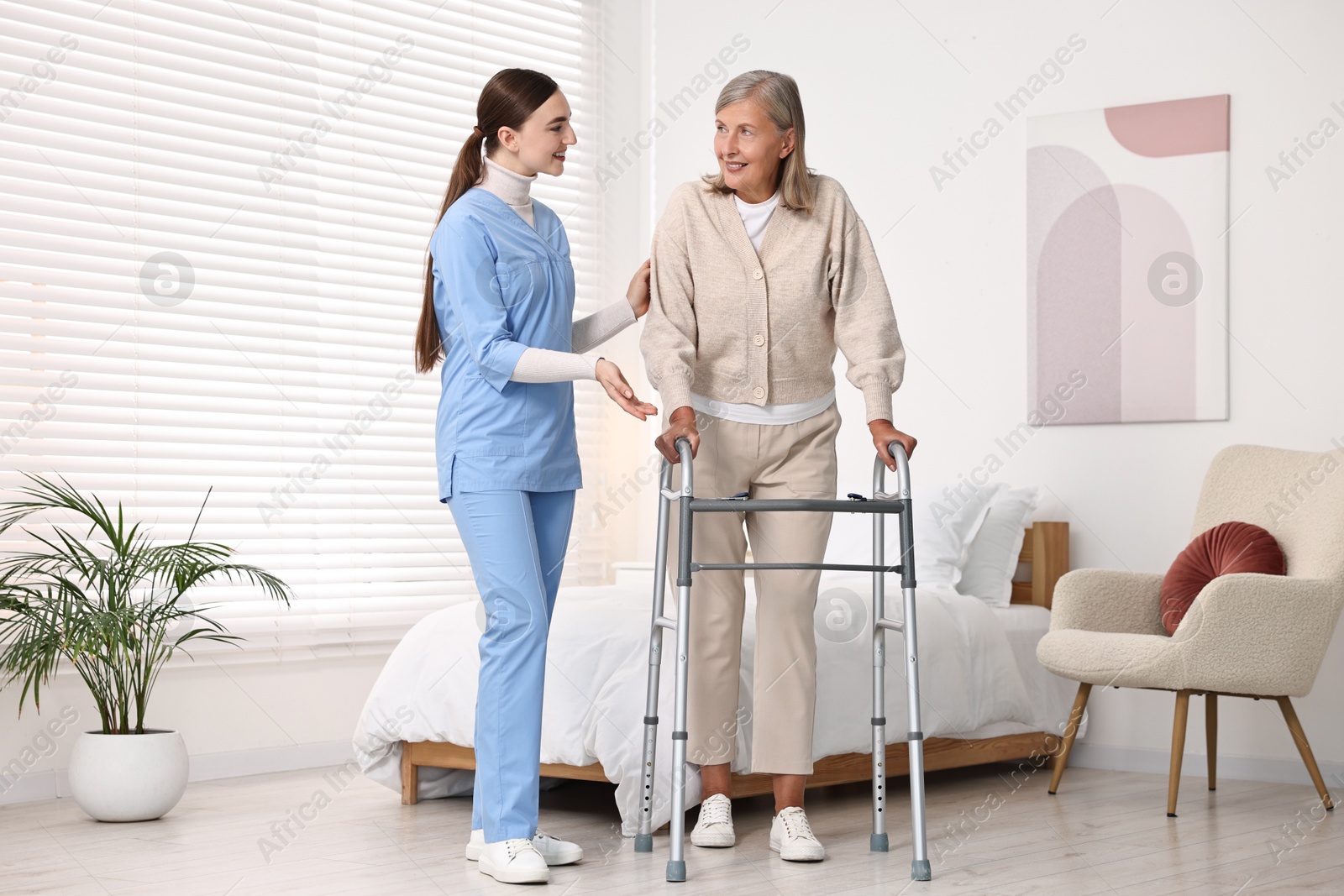 Photo of Nurse helping senior woman with walking frame in clinic