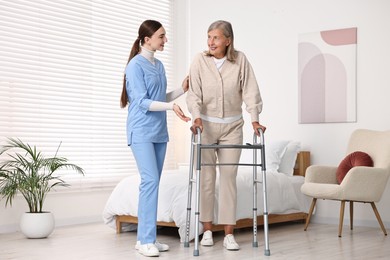 Nurse helping senior woman with walking frame in clinic