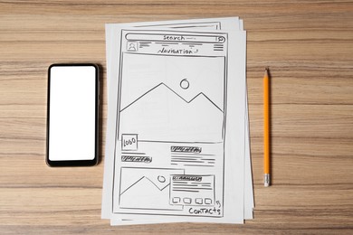 Photo of Website development. Sketches of wireframes, pencil and smartphone on wooden table, flat lay