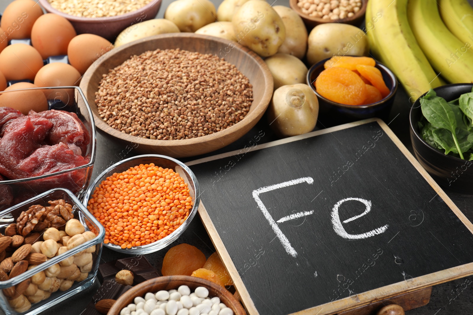 Photo of Diet plan for anemia. Different products rich in iron and small chalkboard with Ferrum symbol on table, closeup