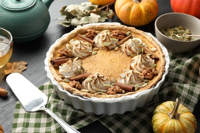 Photo of Homemade pumpkin pie with whipped cream, seeds and cinnamon on grey table