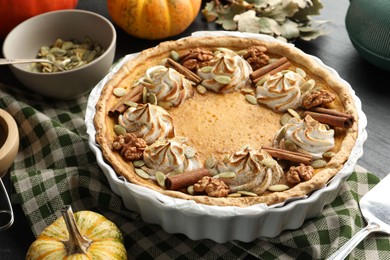 Homemade pumpkin pie with whipped cream, seeds and cinnamon on grey table, closeup