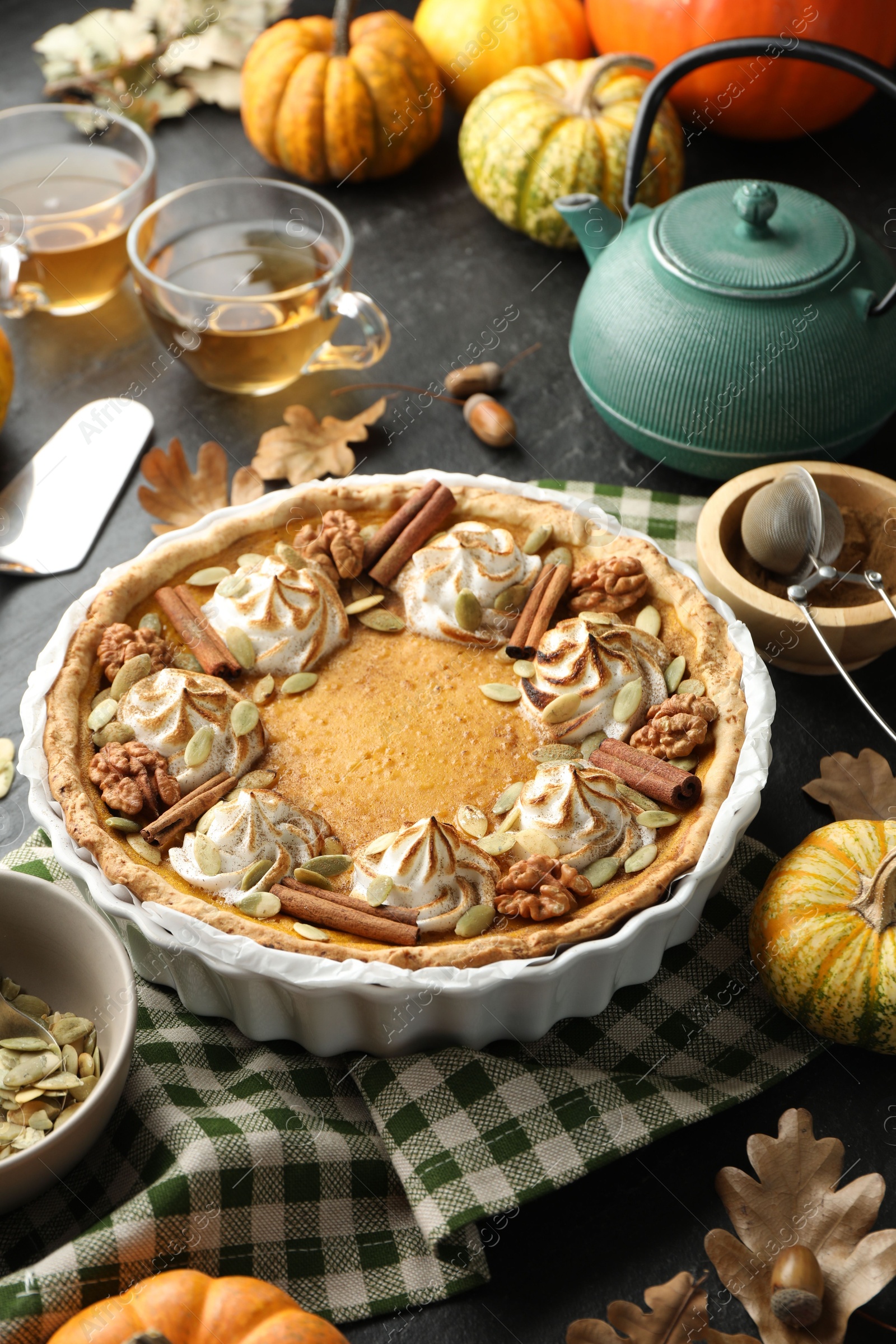 Photo of Homemade pumpkin pie with whipped cream, seeds and cinnamon on grey table