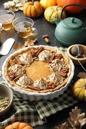 Homemade pumpkin pie with whipped cream, seeds and cinnamon on grey table