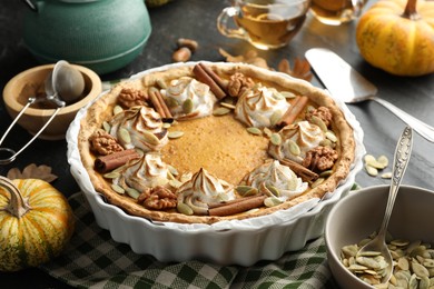 Photo of Homemade pumpkin pie with whipped cream, seeds and cinnamon on grey table