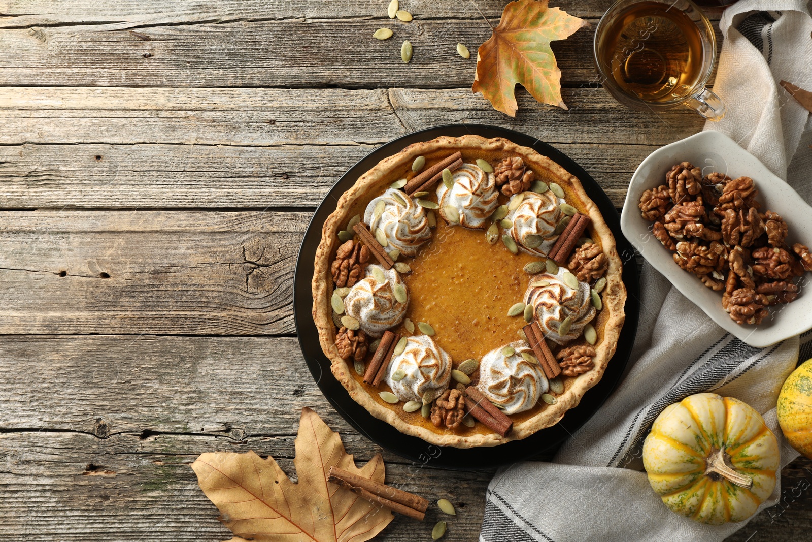 Photo of Flat lay composition with homemade pumpkin pie with whipped cream, seeds and cinnamon on wooden table, space for text