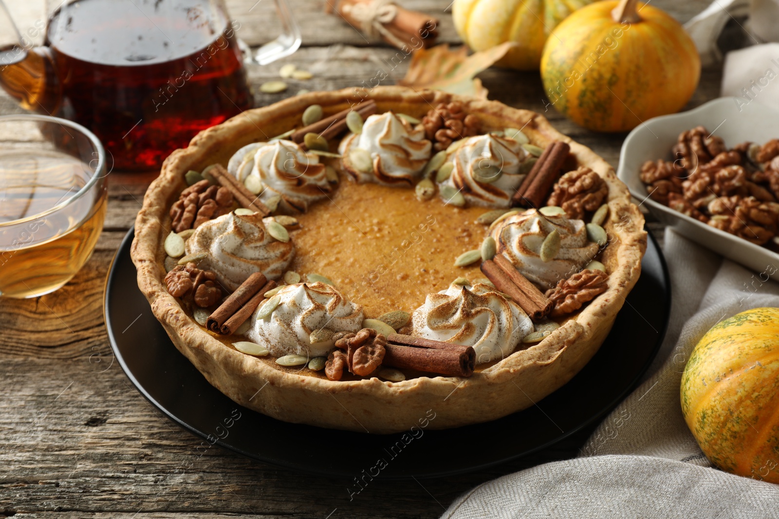 Photo of Homemade pumpkin pie with whipped cream, seeds and cinnamon on wooden table